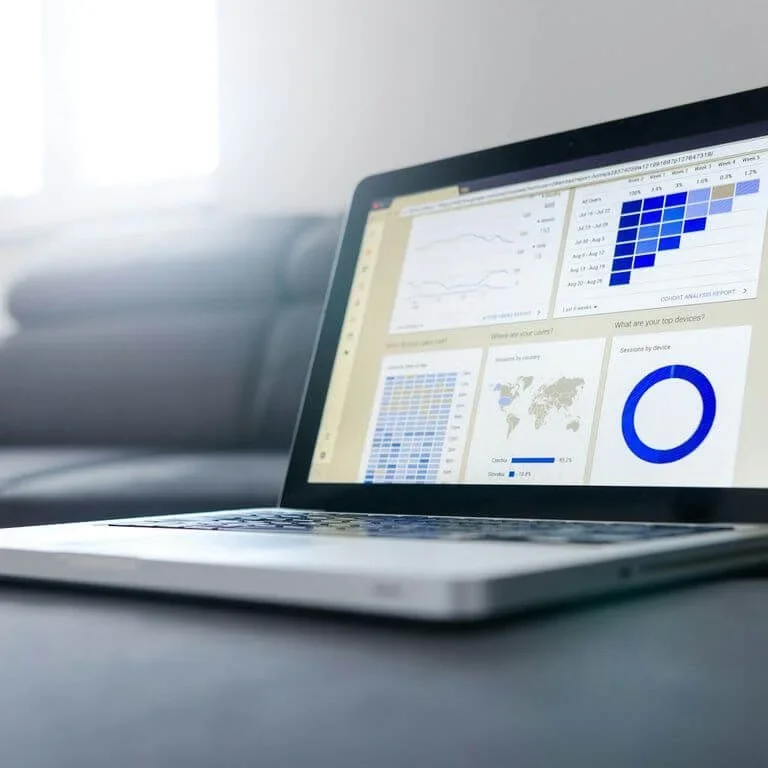 Laptop auf einem Tisch mit Diagrammen und Grafiken auf dem Bildschirm.